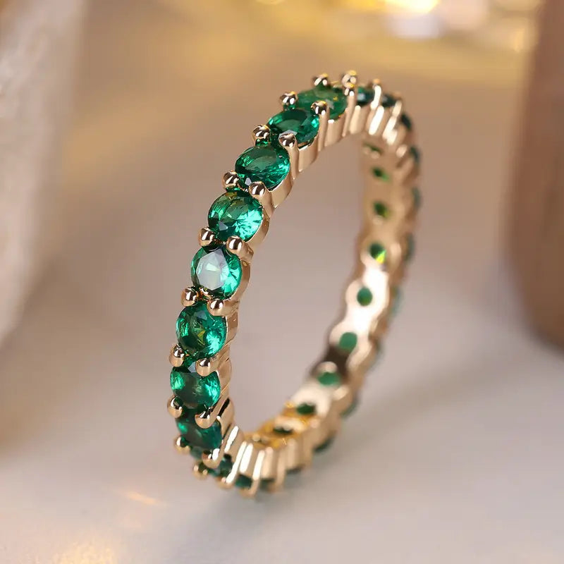 Goldener Ring mit Reihe grüner ovaler Steine und vergoldeter Ringschiene