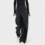 Asymmetrische Hose mit breitem Bein in Schwarz, Knopfverschluss am Bund, schräger Saum. 