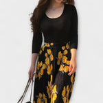 Schwarzes Top mit Rundhalsausschnitt und langem Faltenrock mit gelbem Blumenprint