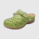 Grüne Holzclogs mit gelochtem Obermaterial und Schnallenriemen, braune Sohle.