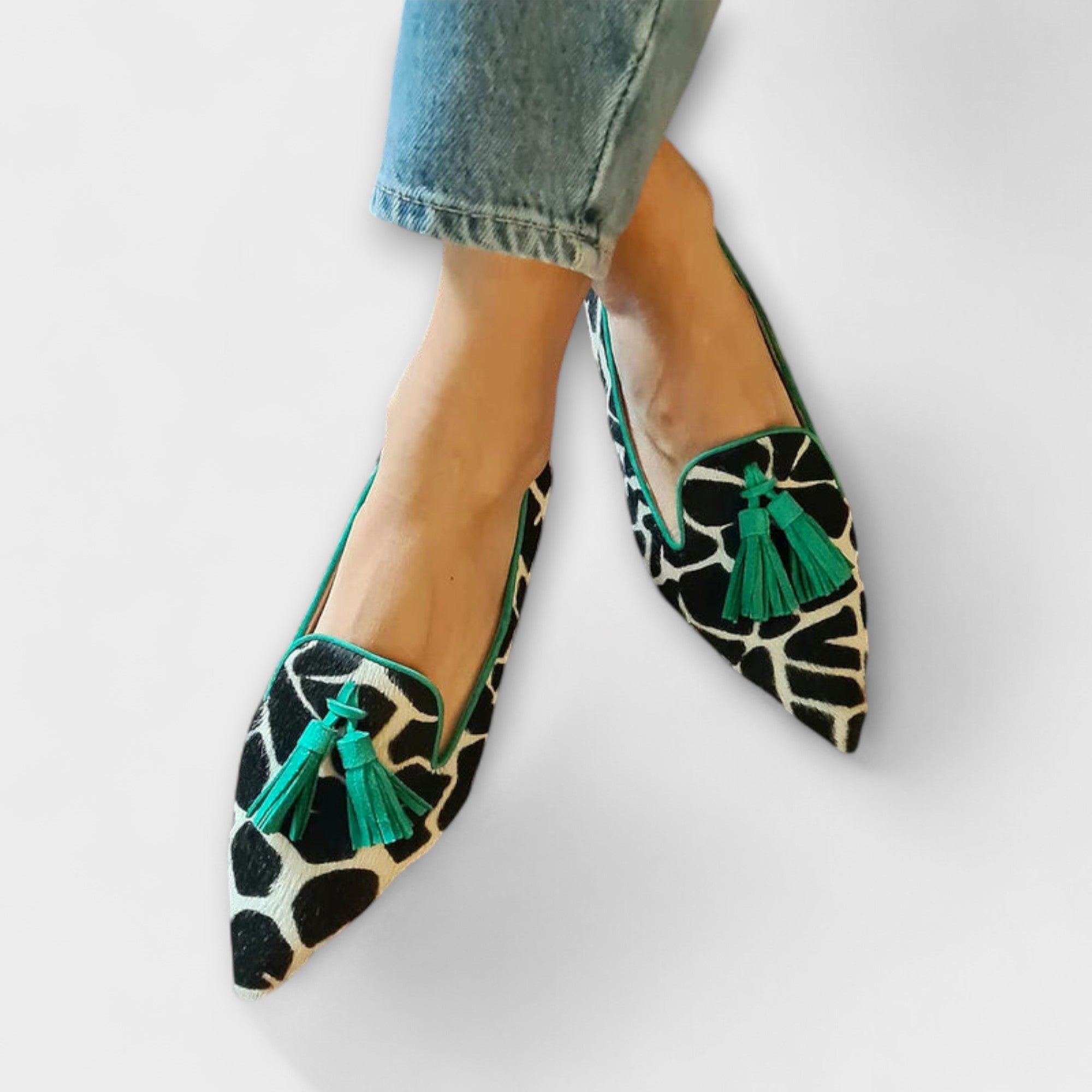 Elegante Slipper mit Kuhfellmuster, schmale Spitze und grüne Quasten