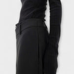 Asymmetrische Hose in Schwarz: Detail am Bund mit Knopf und schmalem Seitendetail.