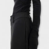 Asymmetrische Hose in Schwarz: Detail am Bund mit Knopf und schmalem Seitendetail.