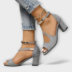 Graue Riemchen-High-Heels mit Blockabsatz, Knöchelriemen und Kettendetail am Fuß