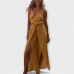 Gelber Jumpsuit mit gekreuztem V-Ausschnitt, ärmellos, Taillenbund und Seitenschlitzen.