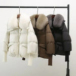 Winterjacken mit Kunstfellkragen in Schwarz, Weiß und Braun nebeneinander am Haken.