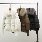 Winterjacken mit Kunstfellkragen in Schwarz, Weiß und Braun nebeneinander am Haken.
