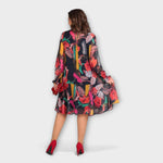 Rückenansicht: weites, gemustertes Kleid mit langen Ärmeln und fließendem Saum