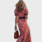 Rückansicht: Rosa Maxi-Kleid mit kurzen Puffärmeln, dunklem Gürtel und Blumenmuster