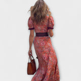 Rückansicht: Rosa Maxi-Kleid mit kurzen Puffärmeln, dunklem Gürtel und Blumenmuster