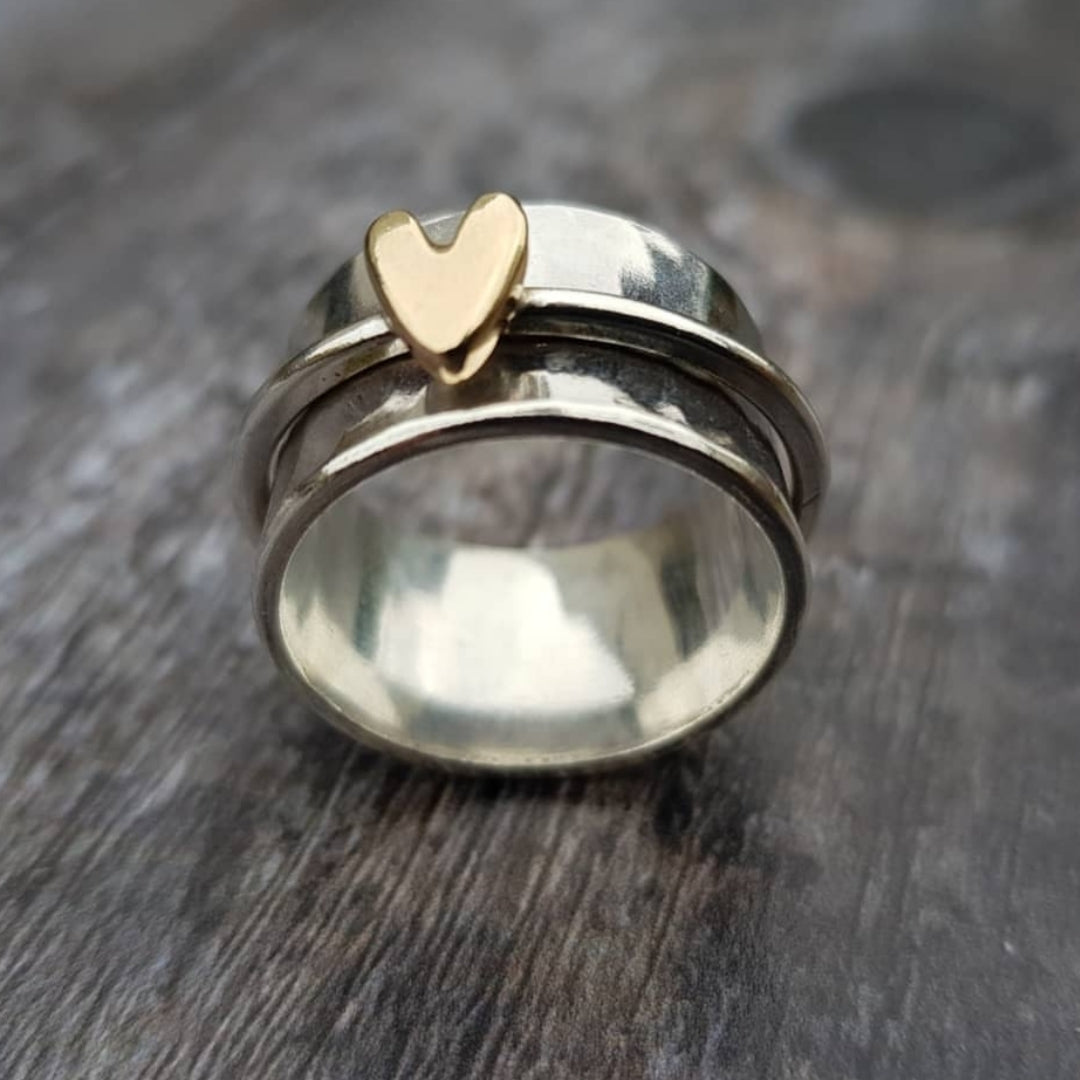 Silberner Ring mit Herz-Detail in Goldton, glänzende Oberfläche