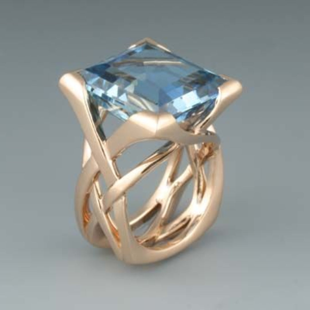 Roségoldfarbener Ring mit blauem quadratischem Stein und offenen Seiten
