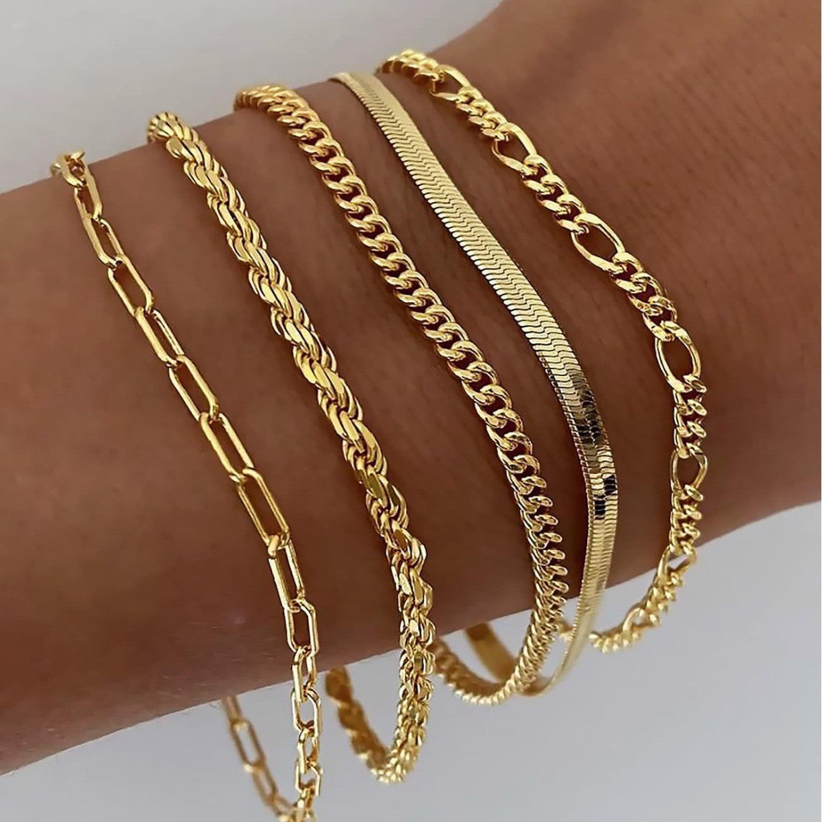 Goldfarbene Armbänder am Handgelenk: Kettenarmband, Gliederkette und breiter Rippeneinsatz