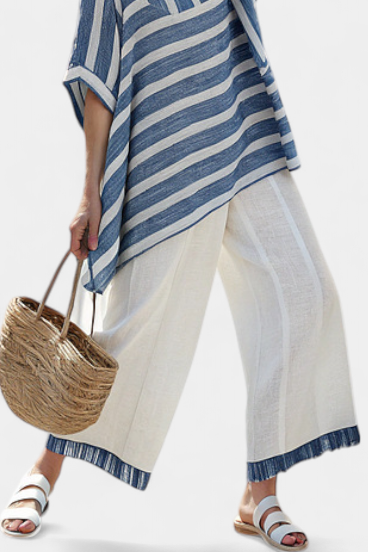 Hellbeige Leinenhose mit blauem Saum; blau gestreifter Überwurf reicht über die Beine