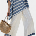Hellbeige Leinenhose mit blauem Saum; blau gestreifter Überwurf reicht über die Beine
