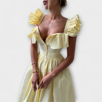 Gelbes Rüschenshirt-Kleid mit gerüschtem Ausschnitt, Knopfleiste vorn und betonter Taille.