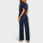 Dunkelblauer Jumpsuit in Seitenansicht, weite Hosenbeine und Bindegürtel in der Taille