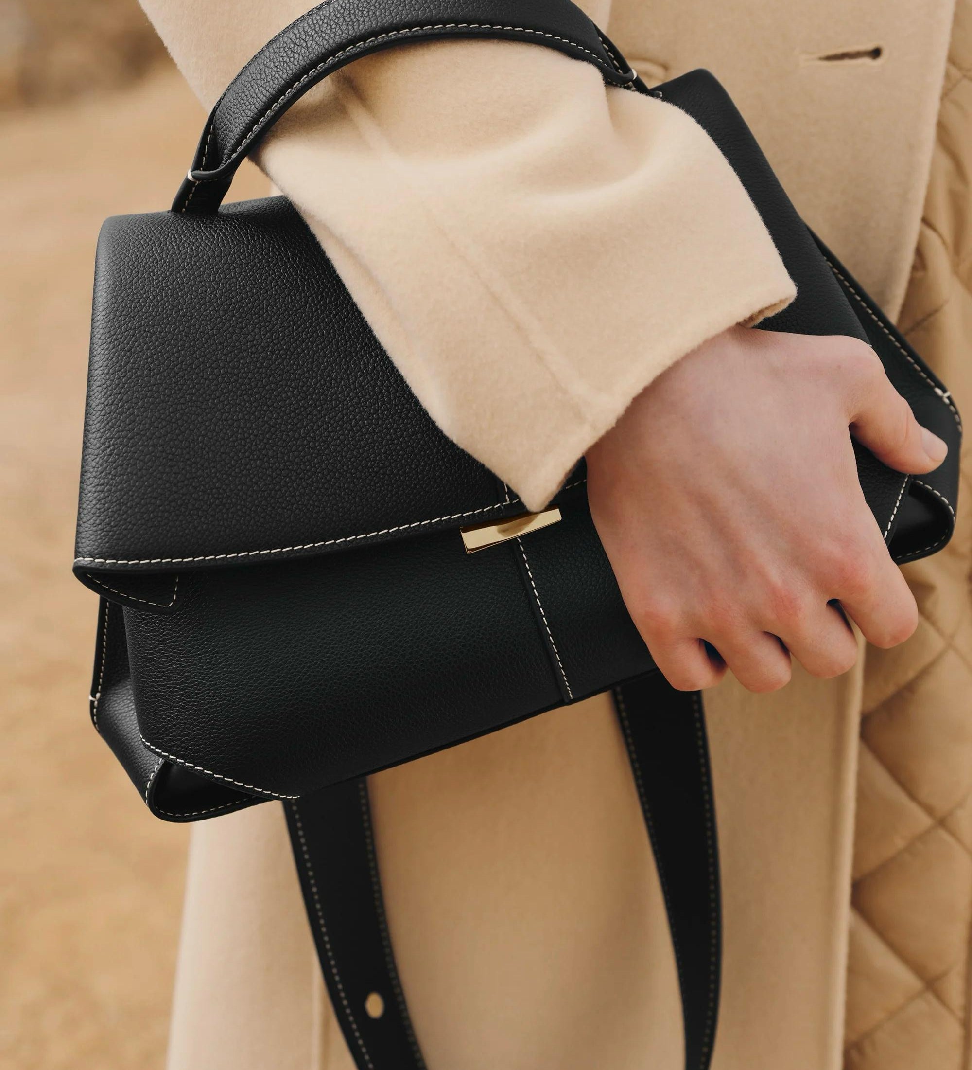Schwarze Handtasche mit Klappdeckel und Schulterriemen, seitlicher Verschlussnaht