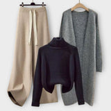 Dreiteiliges Strick-Set: dunkelblauer Turtleneck-Pullover, grauer Strickcardigan, beiger Jogger