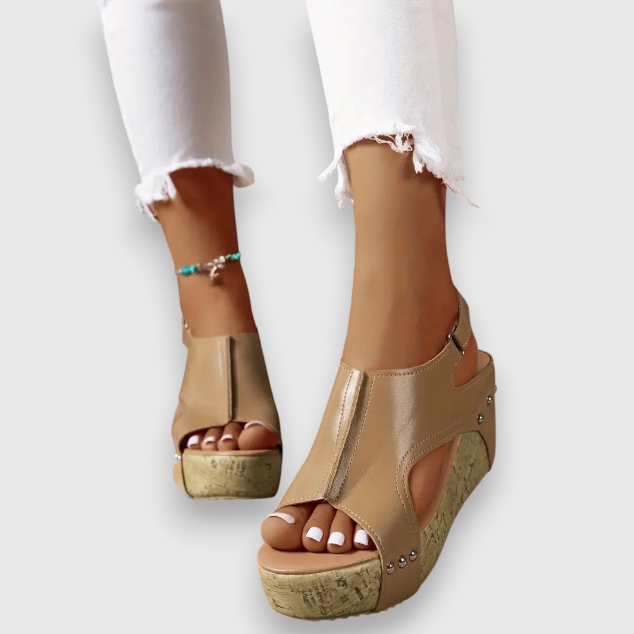Plateau-Sandalen mit offenen Zehen, Knöchelriemen und Nieten, beige mit Kork-Optiksohle.