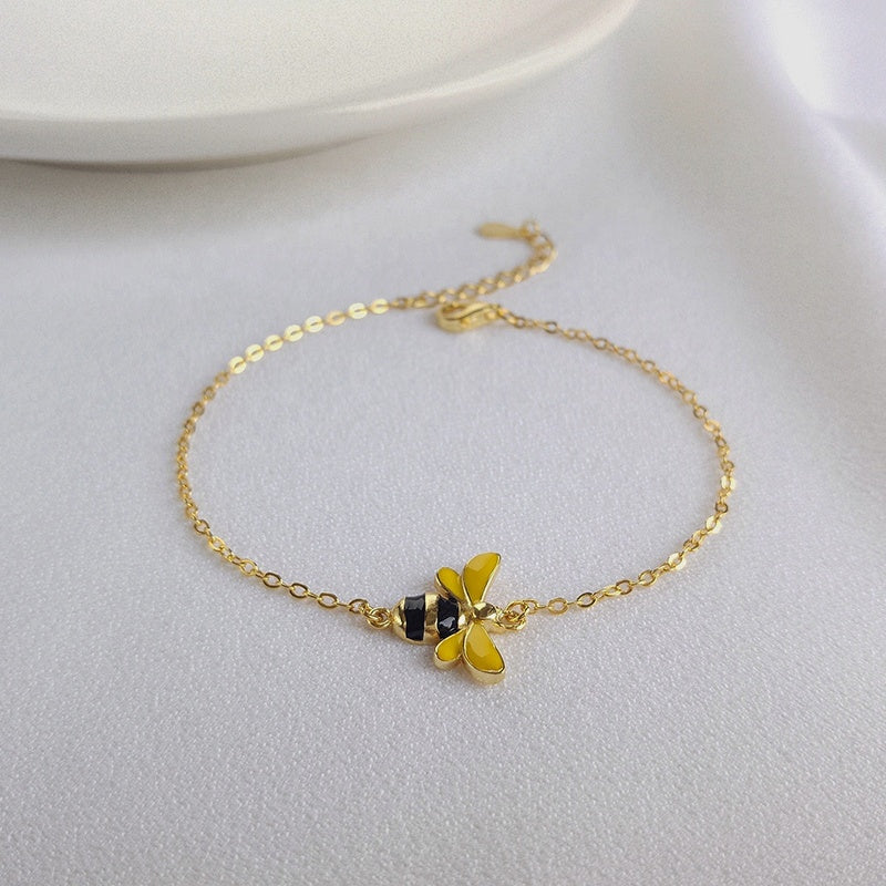 Goldfarbenes Armband mit gelber Blume und dunklem Anhänger, feine Kettenglieder