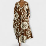 Langes Kleid mit V-Ausschnitt, 3/4-Ärmeln und besticktem Blütenmotiv in Braun und Beige.