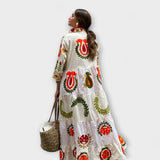 Weißes Blumenkleid mit großen roten Blumenornamenten und grünen Blattranken, weite Länge.