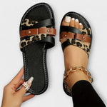 Sandalenpaar mit schwarzem Kreuzriemen, Leopardenmuster-Futter und braunen Metall-Schnallen