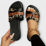 Sandalenpaar mit schwarzem Kreuzriemen, Leopardenmuster-Futter und braunen Metall-Schnallen