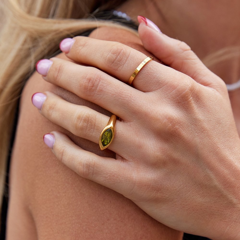 Goldfarbener Ring mit ovalem grünem Kristallstein in geschlossener Fassung