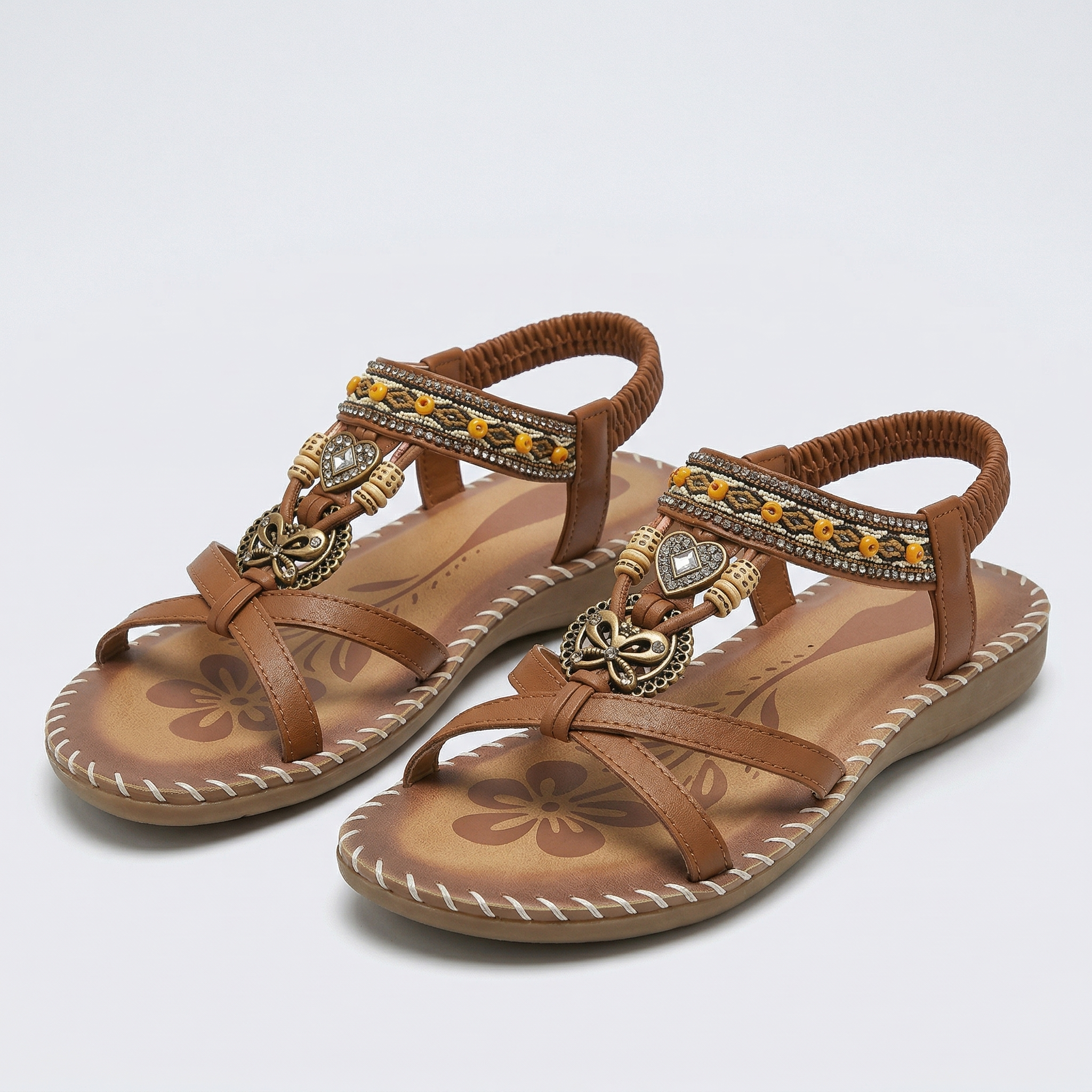 Boho-Sandalen braun, Lederriemen mit Schmuckanhänger, geflochtene Ziernähte, flach
