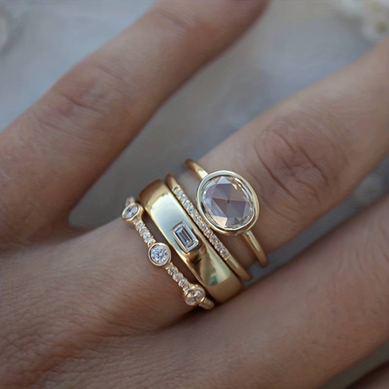 Goldfarbene Ring-Set am Finger mit ovalem Zirkonia und Steinkranz