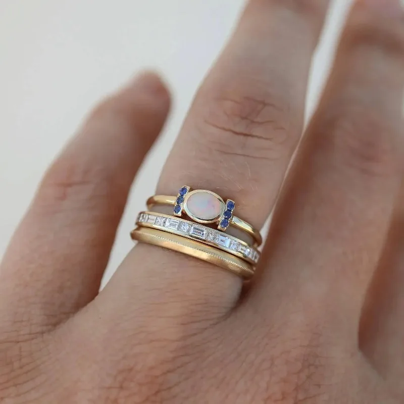 Goldfarbene Ringe am Finger: ovaler Opalstein, blaue Steine und Zirkonia