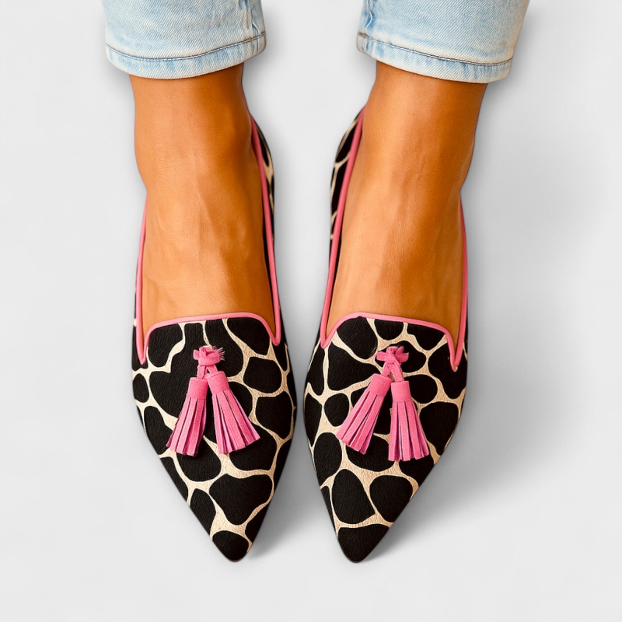 Elegante Slipper mit Kuhfellmuster, spitzer Form und rosa Quasten
