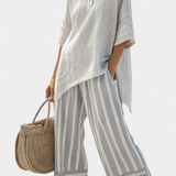 Asymmetrische Bluse mit Knopfleiste und schwingendem Ärmel, dazu gestreifte Hose