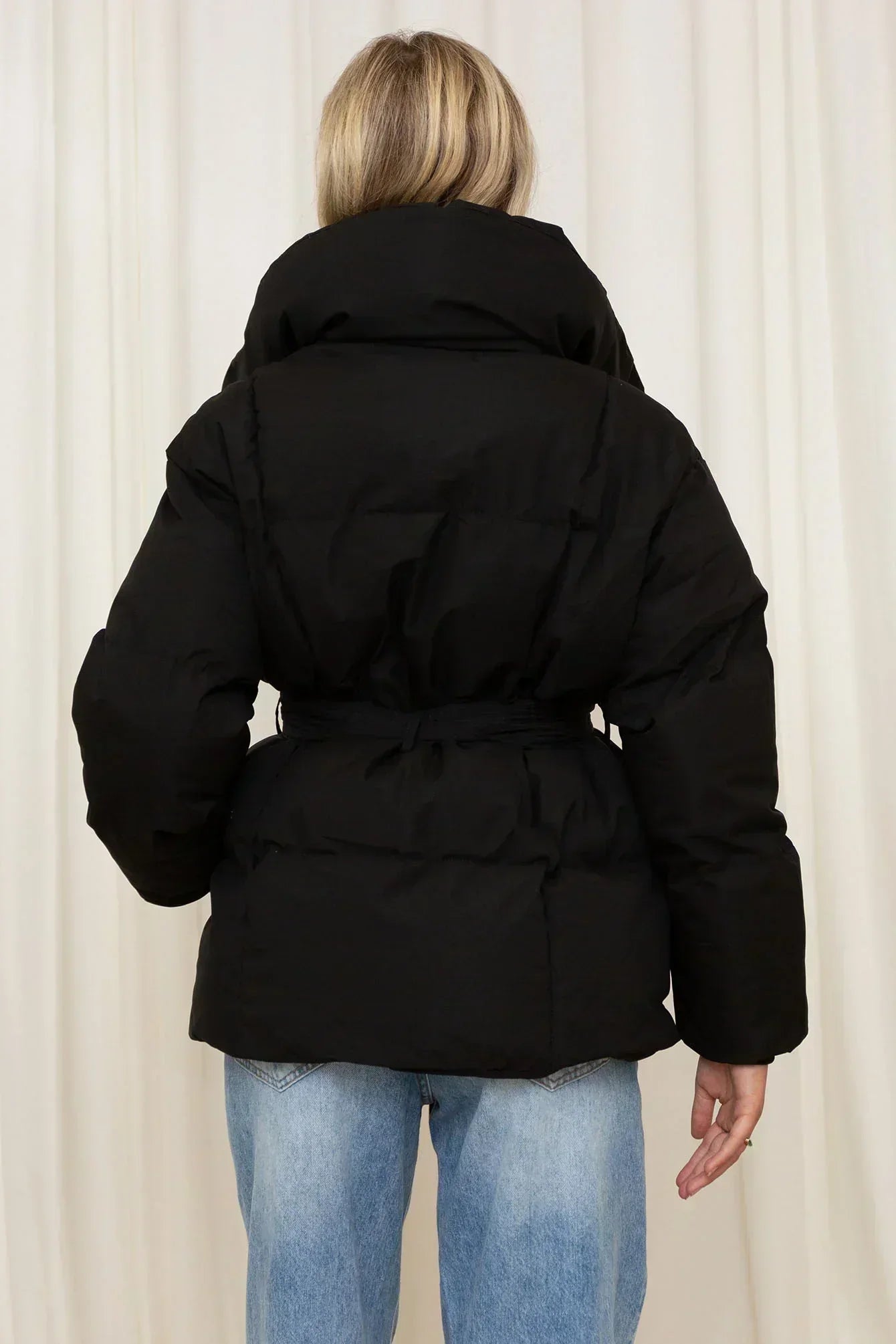 Schwarze Steppjacke von hinten mit Kapuze und Taillengürtel