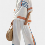 Zweiteiliges Ethno-Set: lockeres Shirt und weite Hose, weiß mit orange-blauen Zierstreifen