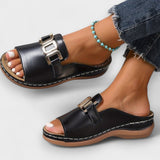 Schwarze Sandalen mit Schnallenverschluss vorn und goldfarbenem Logo-Element, flache Sohle