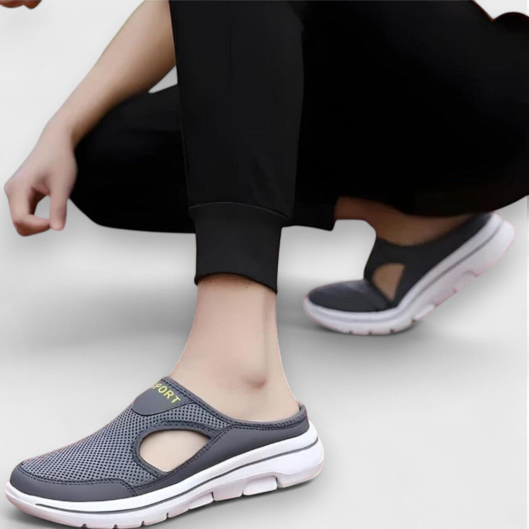 Dunkelgraue Sportsandalen am Fuß mit großer Profilsohle und Aussparung am Rist